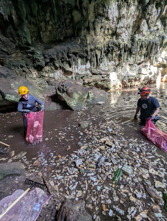 Equipo especializado recogiendo residuos dentro de un cenote